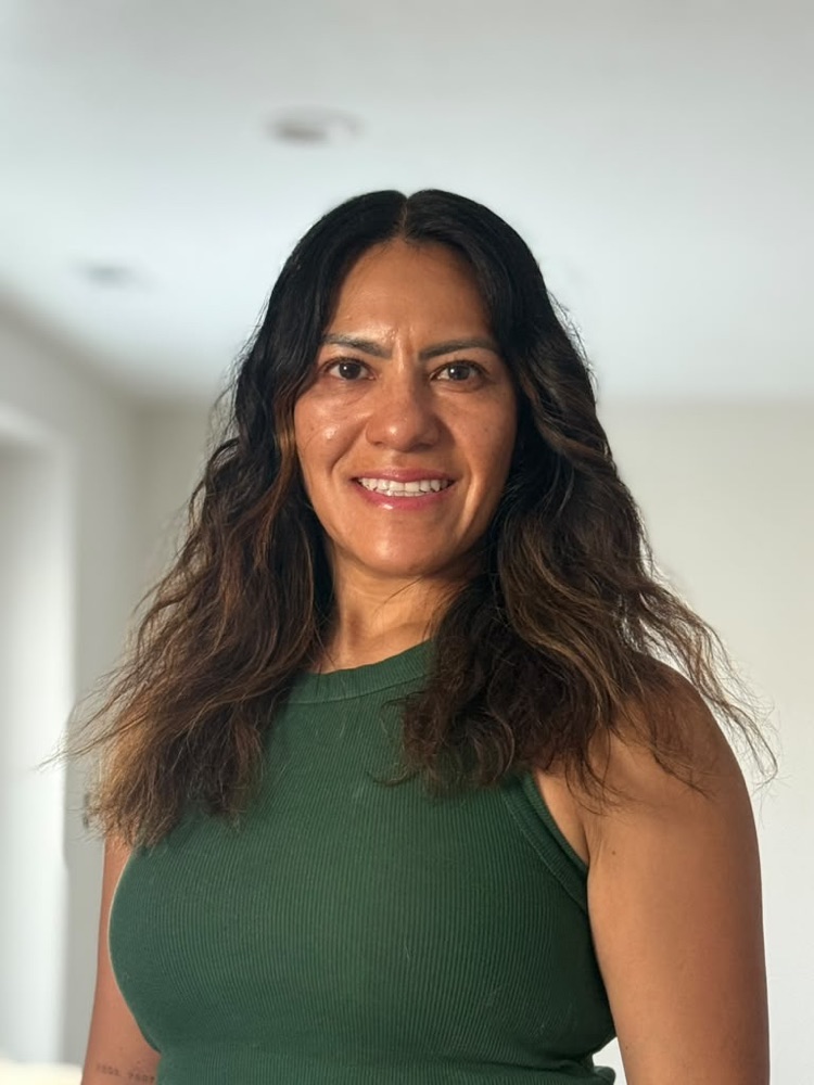 Sue Whetten sonriendo, con el cabello suelto y una blusa verde